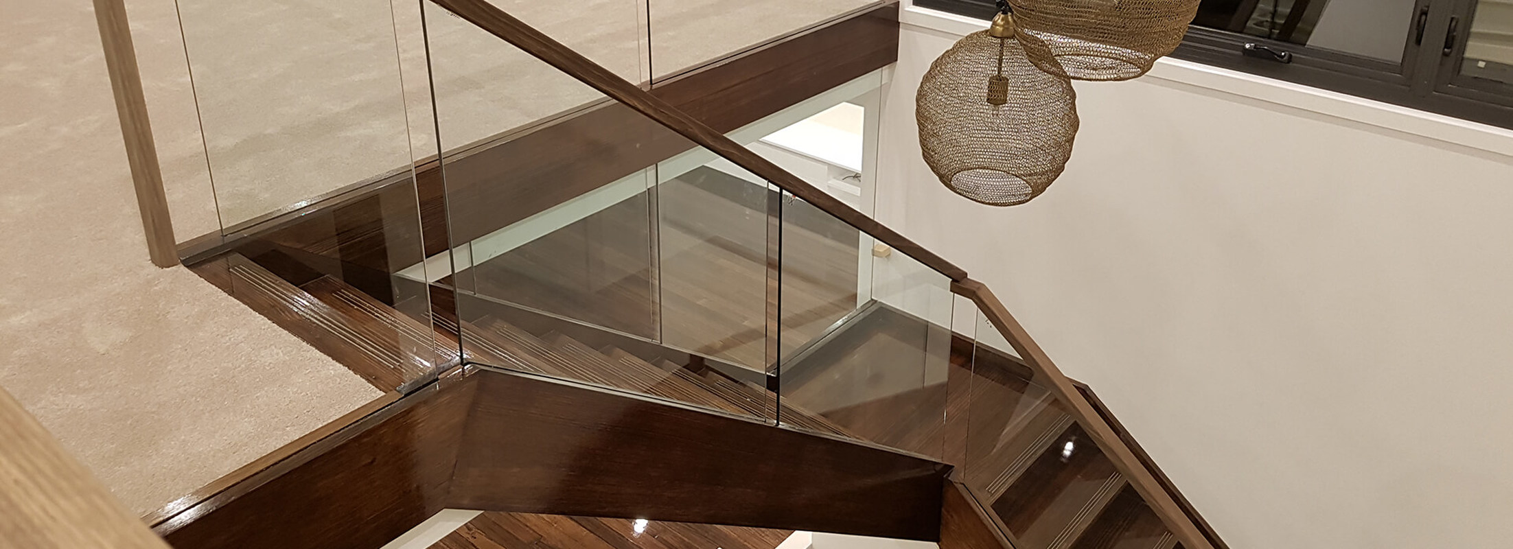 schody drewniane zabiegowe z szklaną balustradą